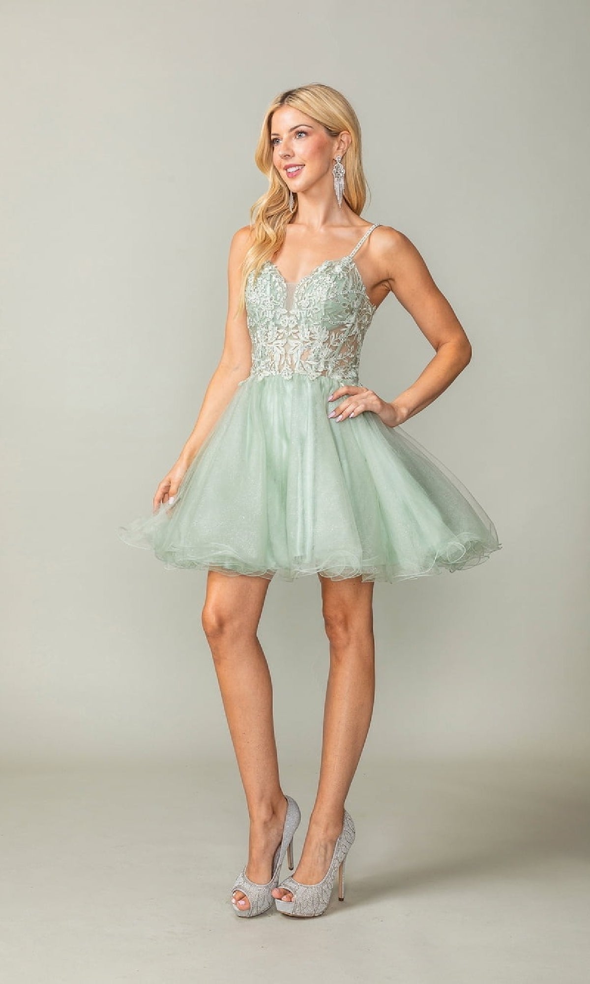 Woman wearing a light green dress with lace details on a plain background